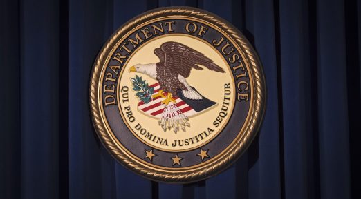 The DOJ logo is pictured on a wall after a news conference in New York